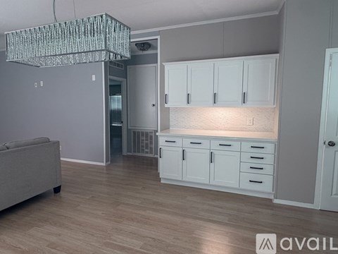 A living room with a grey couch and a chandelier.