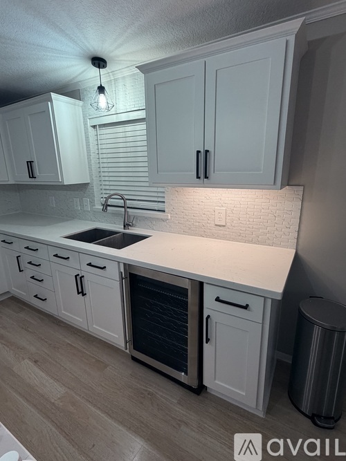 A kitchen with white cabinets and a marble backsplash.