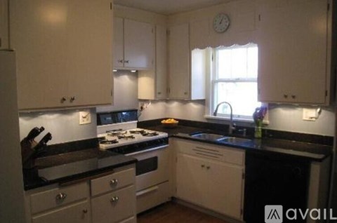 A kitchen with white cabinets and black countertops.