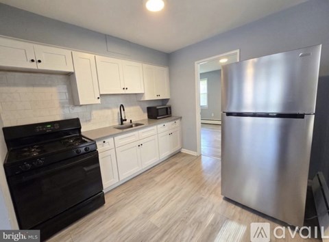 A kitchen with a black stove top oven, white cabinets, and a stainless steel refrigerator.