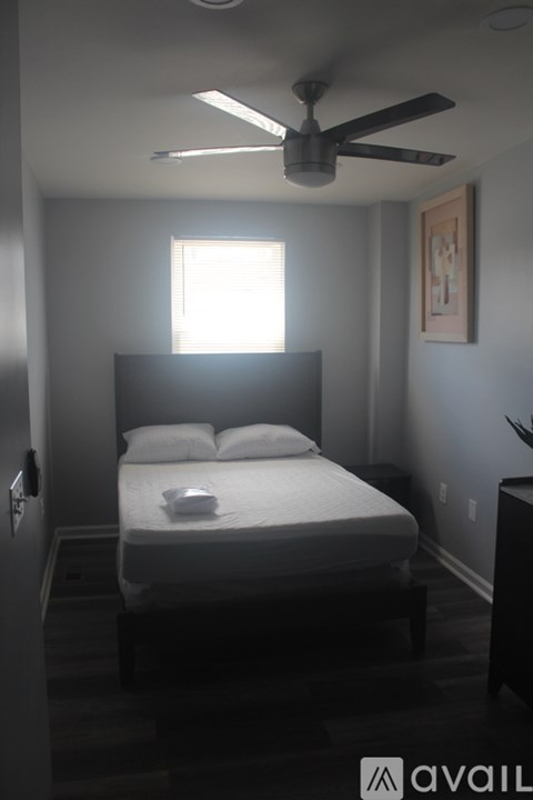 A bedroom with a bed, nightstand, and a ceiling fan.
