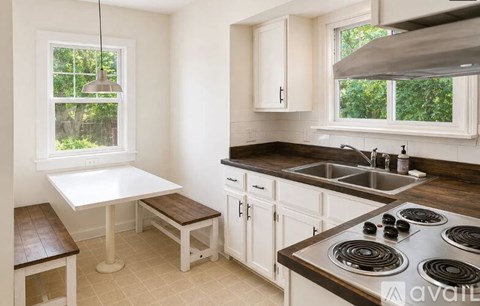 A kitchen with a white table and a stove top oven.