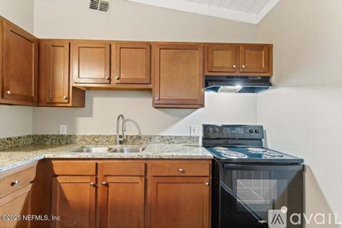A kitchen with wooden cabinets and a black stove top oven.