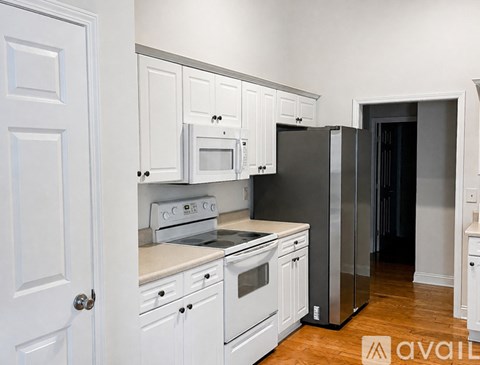 A kitchen with white cabinets and a black refrigerator.