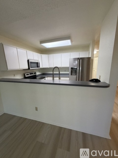 A kitchen with white cabinets and a black countertop.