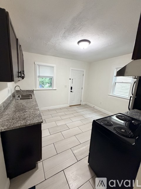 A kitchen with black cabinets and a granite countertop.