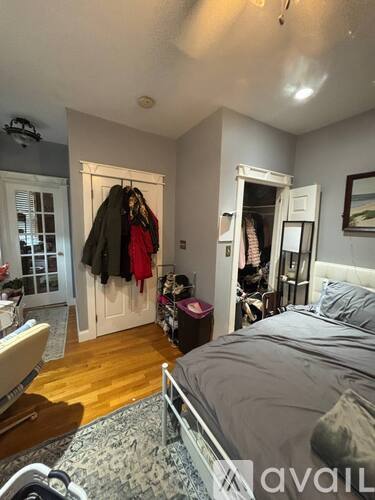 A bedroom with a bed, a chair, and a wardrobe.