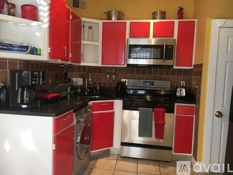 A kitchen with red cabinets and black countertops.