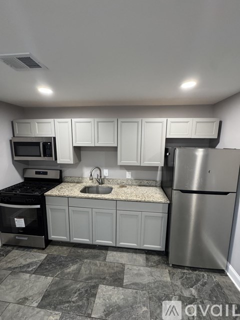 A kitchen with a stainless steel refrigerator, microwave, and oven.