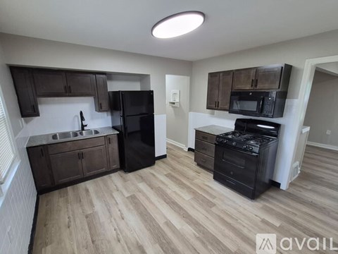 A kitchen with black appliances and wooden floors.
