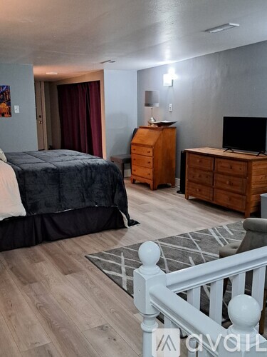 A bedroom with a bed, dresser, and TV.