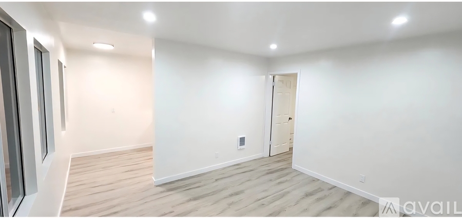A spacious room with wooden flooring and white walls.