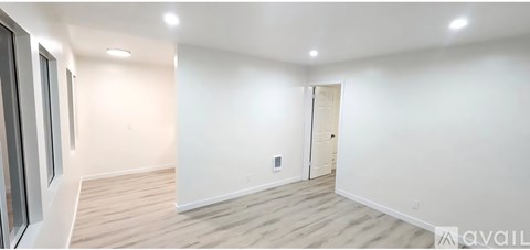 A spacious room with wooden flooring and white walls.