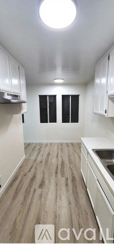 A kitchen with white cabinets and a wooden floor.