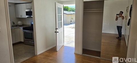 A man is taking a photo of a kitchen with a white oven and wooden floors.