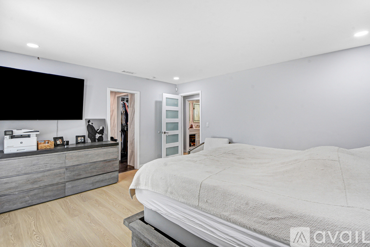 A modern bedroom with a large bed and a TV on the wall.