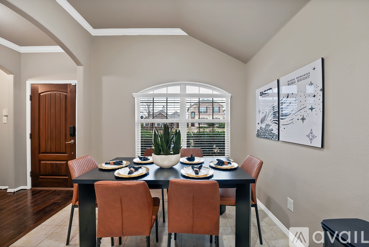 A dining room with a table set for two and a view of a building outside the window.