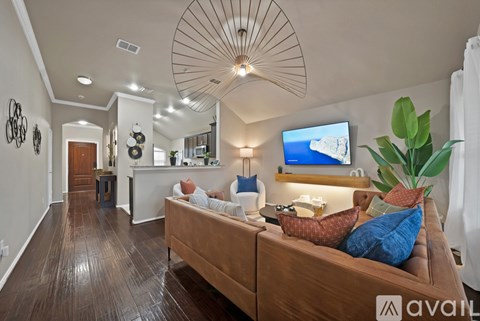 A living room with a brown couch and a television on the wall.