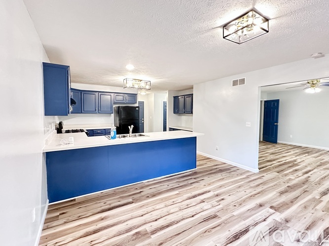A kitchen with blue cabinets and a wooden floor.