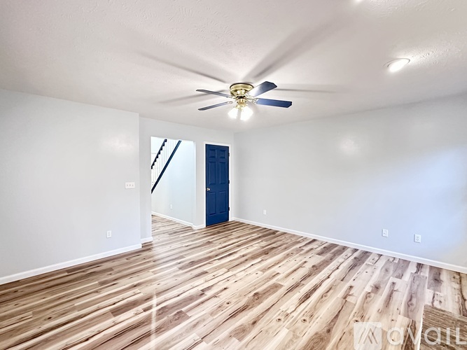 A room with a ceiling fan and wooden flooring.