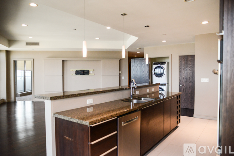 A modern kitchen with dark wood floors and stainless steel appliances.