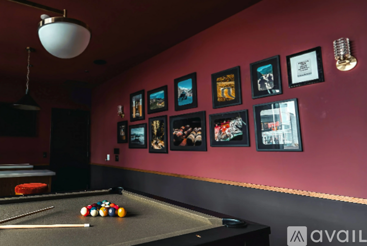 A pool table with a light hanging from the ceiling and pictures on the wall.