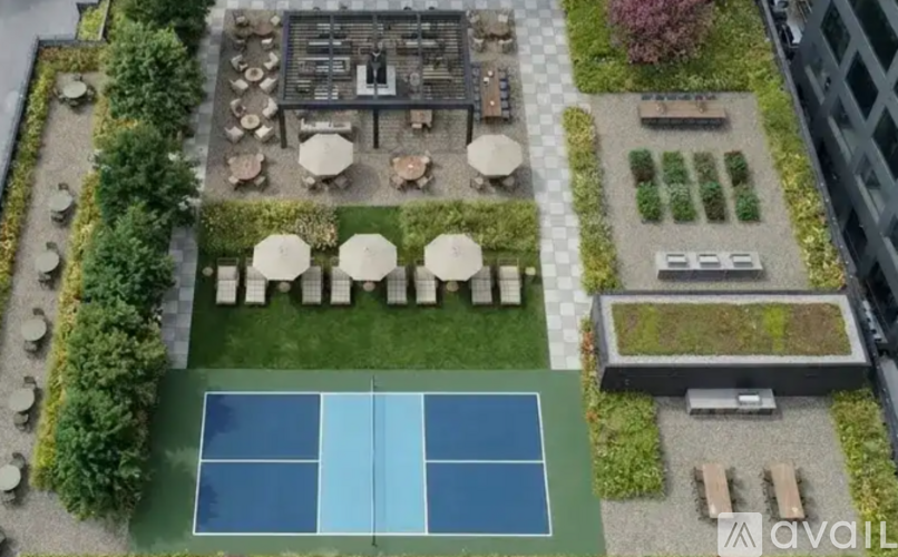 An aerial view of a tennis court surrounded by a garden and a building.