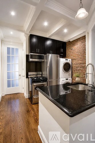 A kitchen with black cabinets and a stainless steel refrigerator.