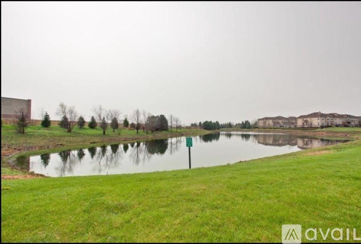 A sign is in the grass by a pond.