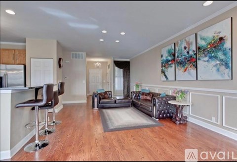 A living room with a grey rug and a painting on the wall.