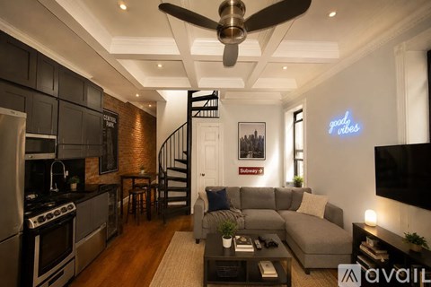 A modern living room with a staircase and a flat screen TV.