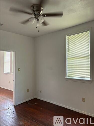 A room with a ceiling fan and a window with blinds.