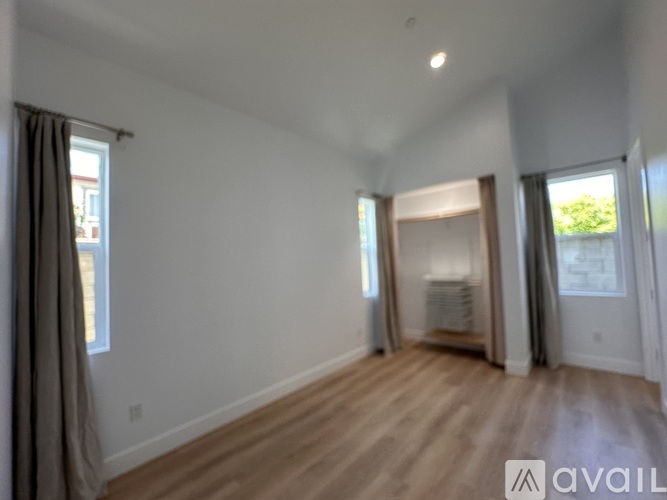 A spacious room with wooden flooring and white walls.