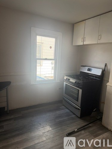 A kitchen with a black stove top oven and wooden flooring.