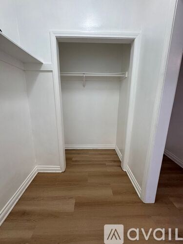 A white closet with a wooden floor and a hanger.