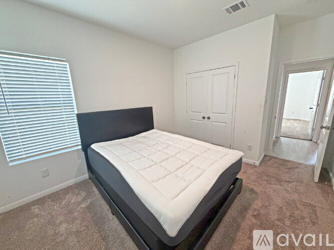 A bedroom with a large bed and a carpeted floor.