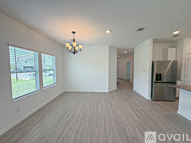 A spacious living room with wood flooring and a chandelier.
