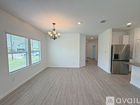 A spacious living room with wood flooring and a chandelier.