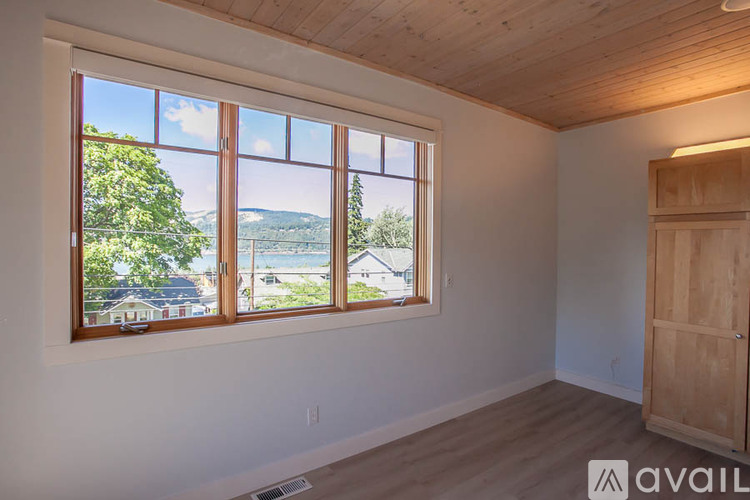 A room with a large window overlooking a lake and trees.