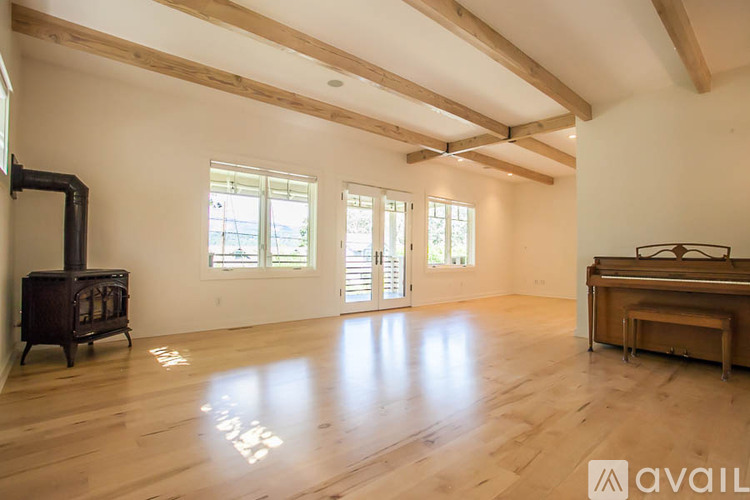 A spacious room with wooden floors and a large window.