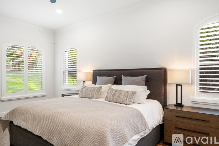 A bedroom with a large bed and two lamps.