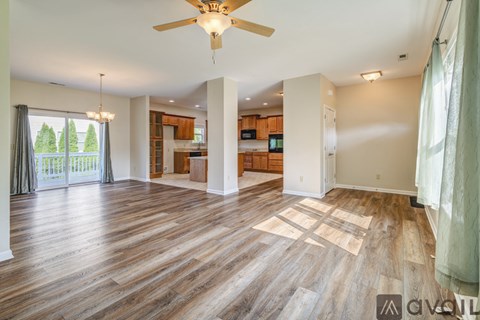 A spacious living room with hardwood floors and a ceiling fan.