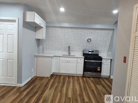 A kitchen with white cabinets and a brick backsplash.