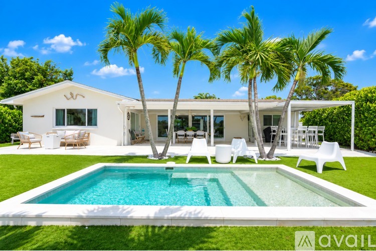 A white house with a pool and palm trees.