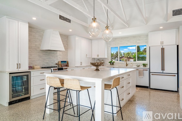 A kitchen with white cabinets and a large island with two bar stools.