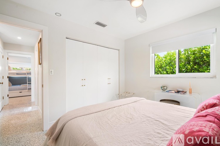 A bedroom with a large bed and a window overlooking a green area.