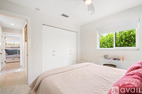 A bedroom with a large bed and a window overlooking a green area.