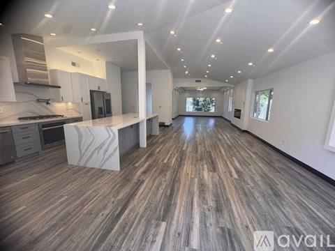 A spacious kitchen with a marble island and wooden flooring.