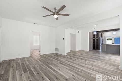 A spacious room with a ceiling fan and wooden flooring.