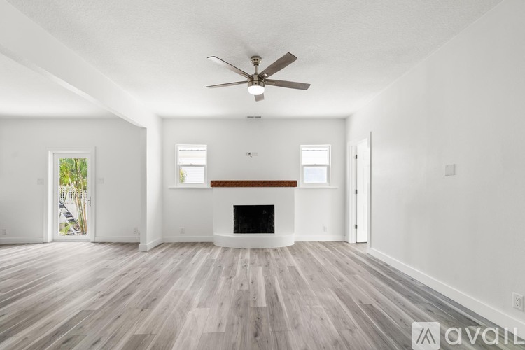 A spacious living room with a fireplace and a ceiling fan.